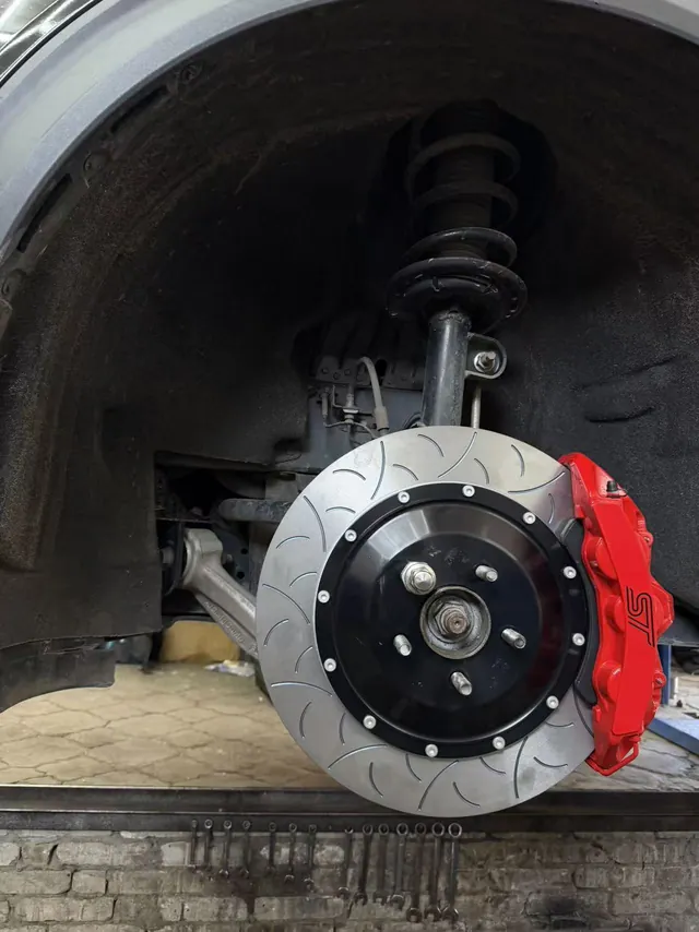 Customer-supplied close-up of a red caliper and slotted rotor with the wheel removed.