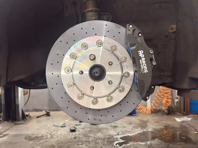 Black front caliper and drilled rotor on a Toyota Alphard with the wheel removed.