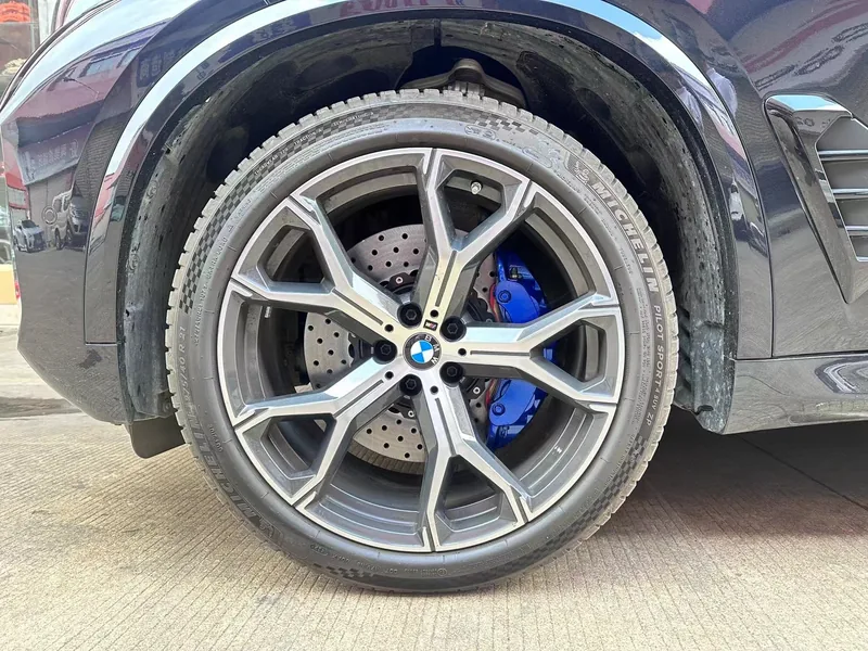 Six-piston caliper and drilled rotor behind a BMW alloy wheel