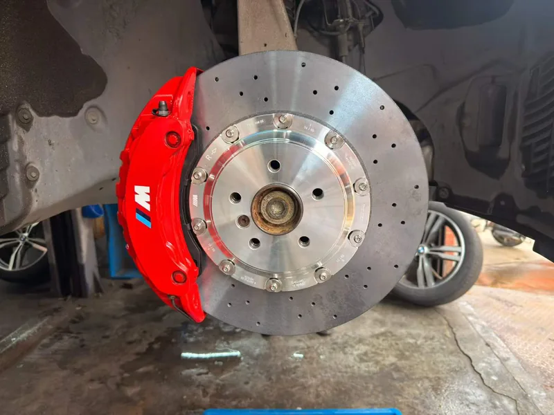 Red six-piston caliper and two-piece drilled rotor on a vehicle hub