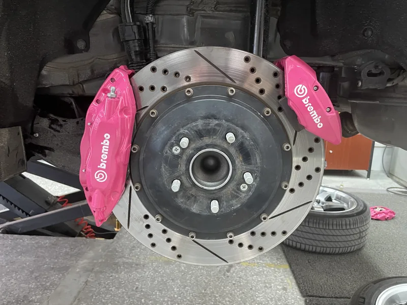 Twin pink four-piston calipers on a slotted and drilled rotor