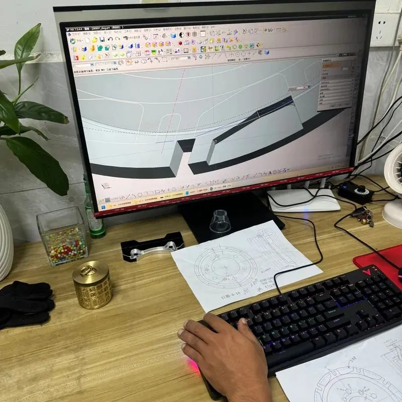 CAD drawing of a brake part on screen beside a finished bracket sample