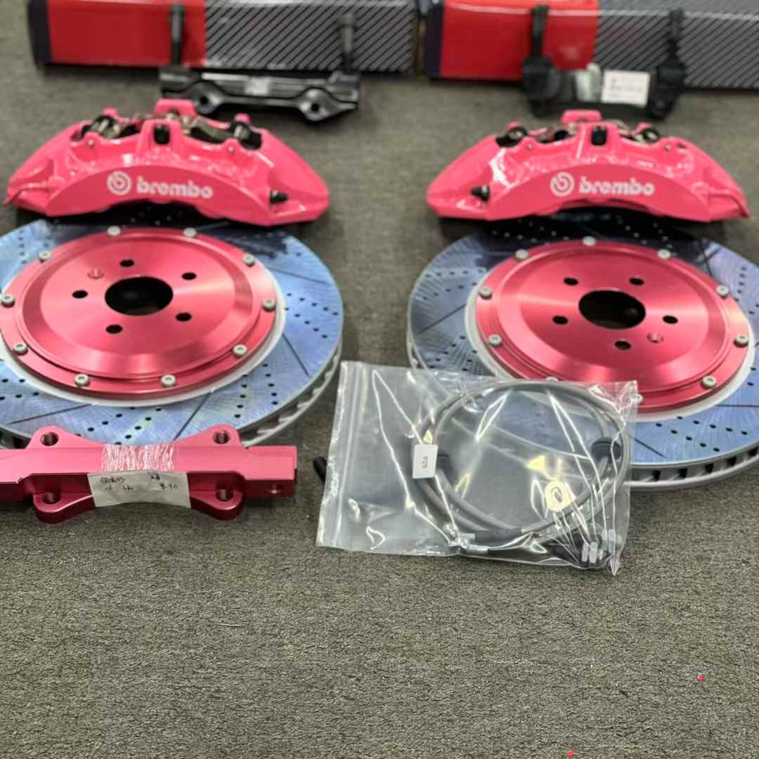 Complete front brake kit layout with pink six-piston calipers, drilled rotors, adapter bracket and brake hoses