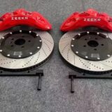Technician checking front caliper clearance against the wheel spokes and inner barrel during fitment approval.