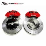 Pair of red front brake calipers with drilled rotors and adapter brackets arranged as a complete kit.