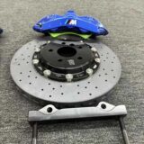 Close view of a GT6 six-piston front caliper, adapter bracket and rotor interface for BMW F30 fitment review.