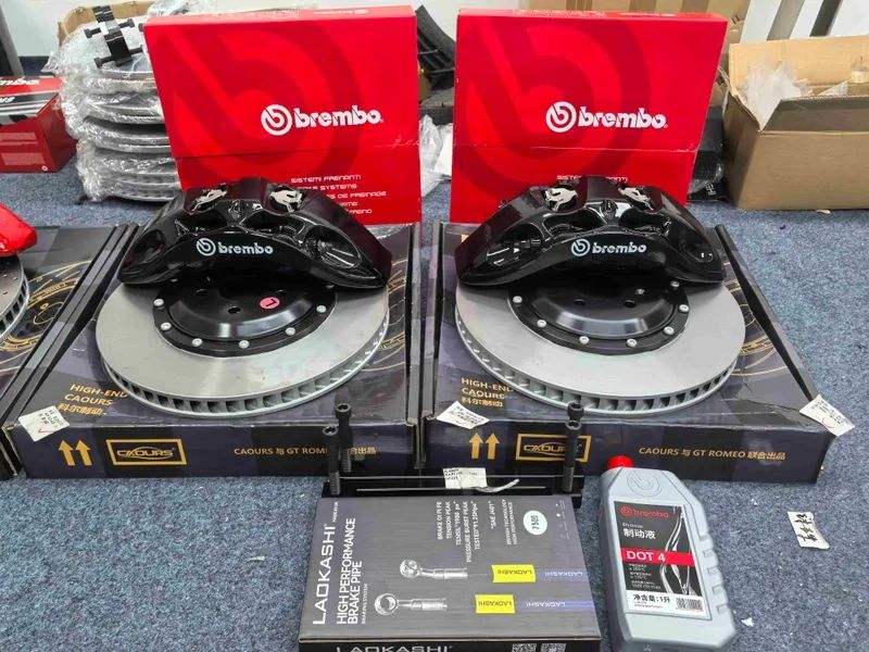 Pair of black front brake calipers displayed with two ventilated rotors and boxed components