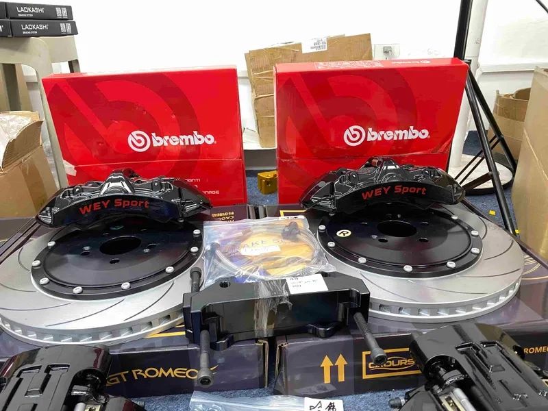 Front brake kit display showing black calipers, slotted two-piece rotors, pads and hoses