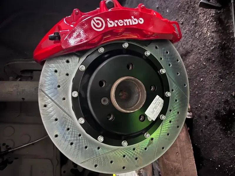 Front brake caliper and drilled rotor shown in an installed-hub clearance reference