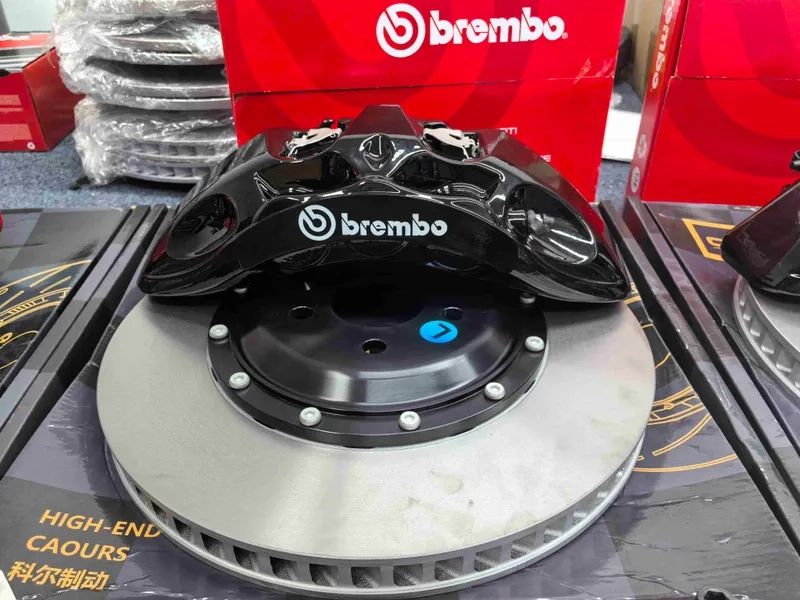 Close view of a black front brake caliper positioned above a ventilated two-piece rotor