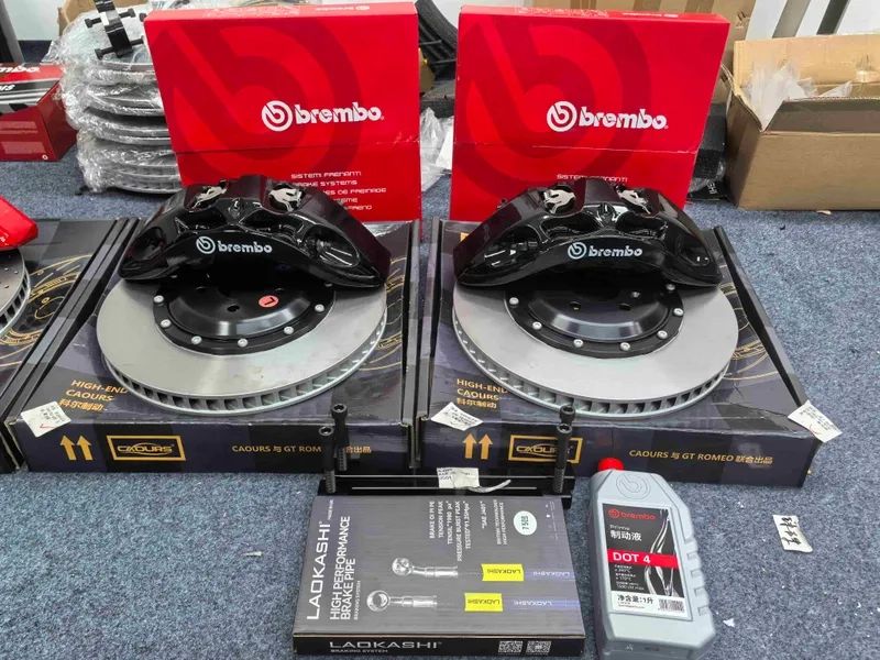 Two black brake calipers and ventilated rotors arranged with brake hoses and fluid containers