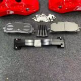 Complete BMW X5 E70 big brake kit laid out with two calipers, two adapter brackets, two rotors, four pads and two hoses